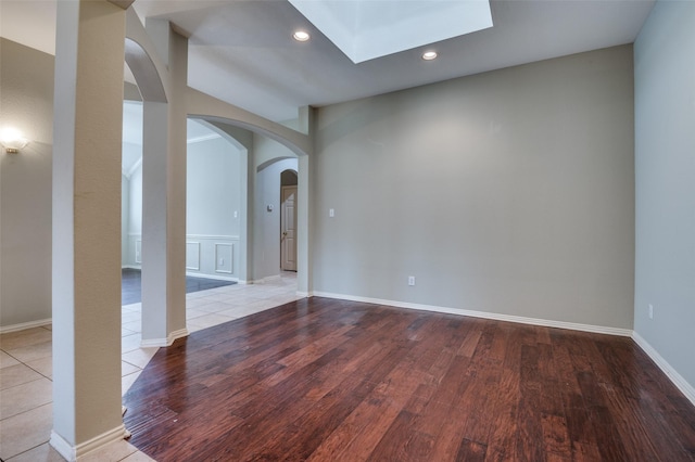 empty room featuring a skylight and light hardwood / wood-style floors