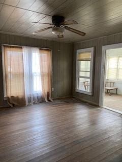 unfurnished room with ceiling fan, wooden walls, wood ceiling, and dark hardwood / wood-style flooring