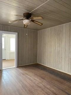 spare room featuring ceiling fan, wood-type flooring, wooden walls, and wooden ceiling