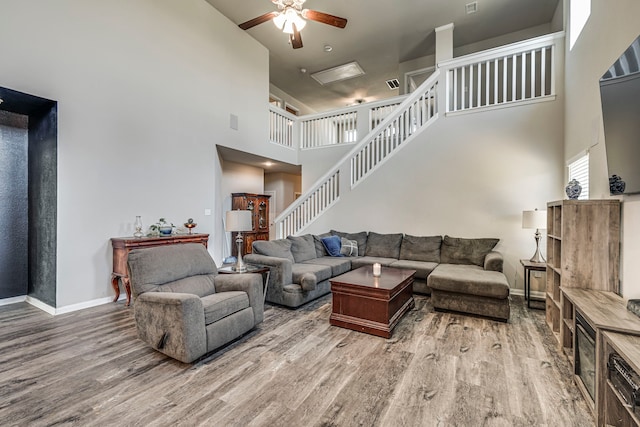 living room with wood-type flooring, a towering ceiling, and ceiling fan