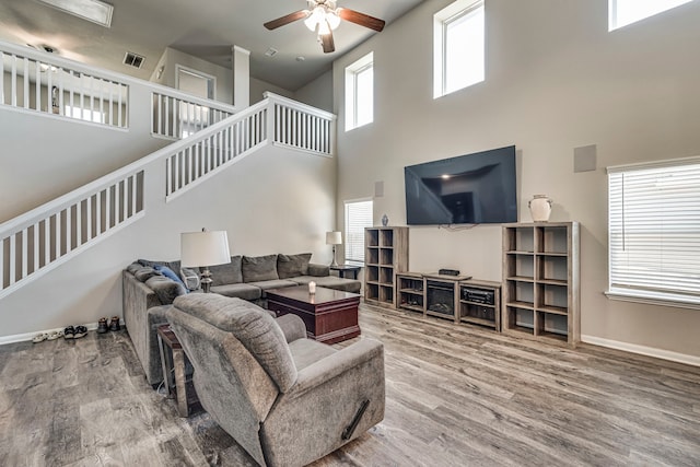 living room featuring a towering ceiling, wood-type flooring, and ceiling fan