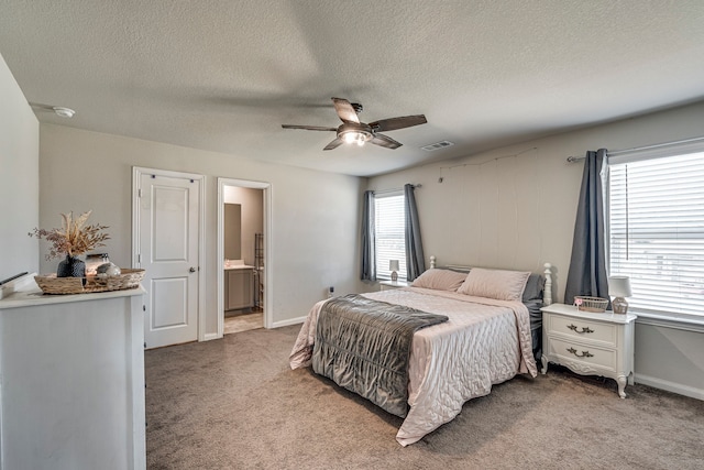 carpeted bedroom with ensuite bath, a textured ceiling, and ceiling fan