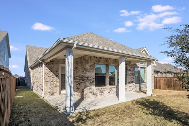 rear view of house featuring a yard, brick siding, a patio area, and a fenced backyard