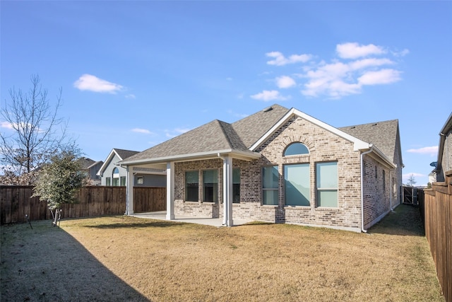 rear view of house featuring a yard, brick siding, a patio area, and a fenced backyard