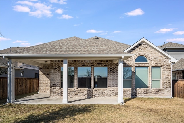 back of house featuring a patio area, brick siding, fence, and roof with shingles