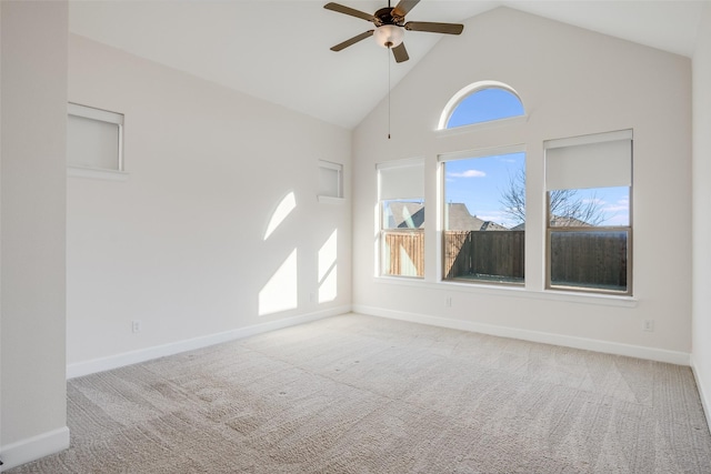 carpeted spare room featuring plenty of natural light, high vaulted ceiling, ceiling fan, and baseboards