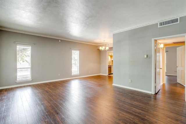 spare room with ornamental molding, dark hardwood / wood-style floors, a textured ceiling, and a notable chandelier