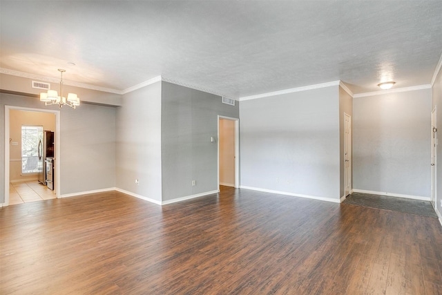 empty room featuring hardwood / wood-style floors, crown molding, and a chandelier