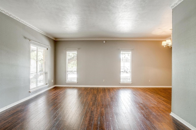 spare room featuring ornamental molding, dark hardwood / wood-style floors, a wealth of natural light, and an inviting chandelier