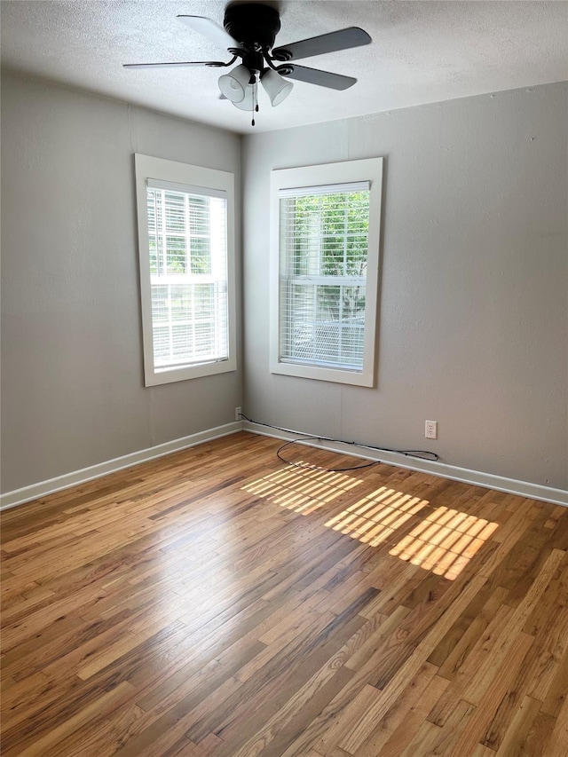 unfurnished room with hardwood / wood-style floors, a textured ceiling, a wealth of natural light, and ceiling fan