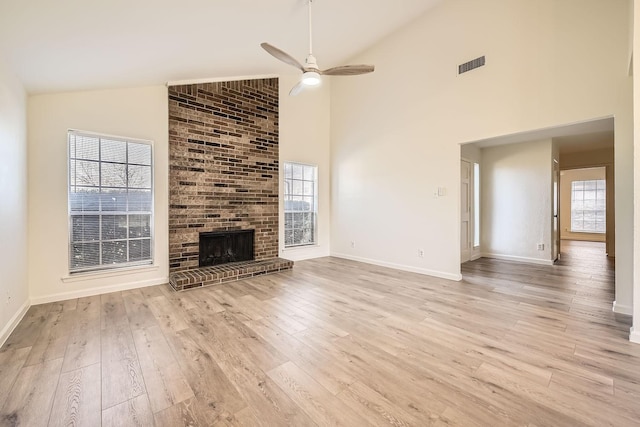 unfurnished living room with a healthy amount of sunlight, light hardwood / wood-style floors, and a brick fireplace