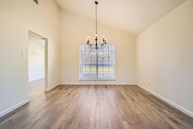 unfurnished dining area featuring hardwood / wood-style flooring, high vaulted ceiling, and a notable chandelier