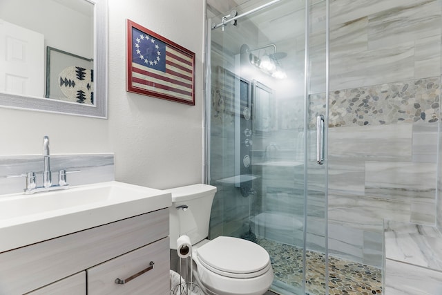 bathroom featuring vanity, a shower with door, and toilet