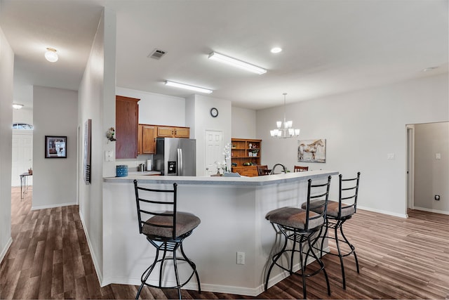 kitchen with brown cabinets, visible vents, a breakfast bar, and stainless steel fridge with ice dispenser