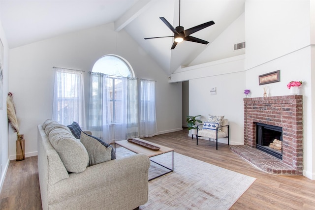 living room featuring hardwood / wood-style floors, high vaulted ceiling, a fireplace, ceiling fan, and beam ceiling