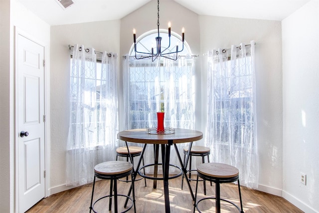 dining room with lofted ceiling, hardwood / wood-style floors, and a chandelier