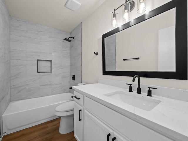 full bathroom with tiled shower / bath combo, vanity, hardwood / wood-style floors, and toilet