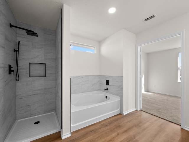 bathroom with hardwood / wood-style floors and separate shower and tub