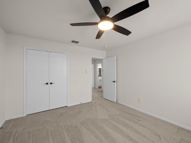 unfurnished bedroom featuring ceiling fan, light colored carpet, and a closet