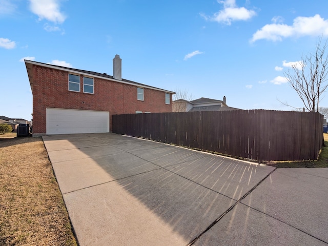 view of side of home with a garage and central AC