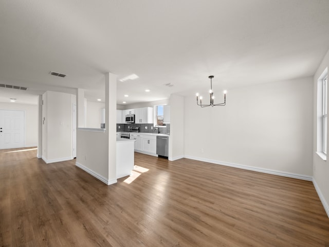 interior space with white cabinets, a chandelier, dark hardwood / wood-style flooring, decorative backsplash, and stainless steel appliances