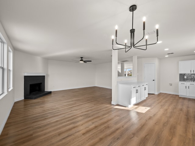 unfurnished living room featuring ceiling fan, light hardwood / wood-style flooring, a brick fireplace, and a wealth of natural light