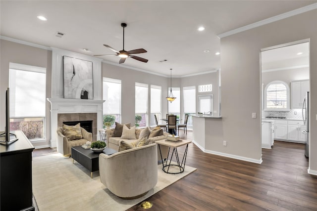 living room featuring ornamental molding, ceiling fan, a fireplace, and dark hardwood / wood-style flooring