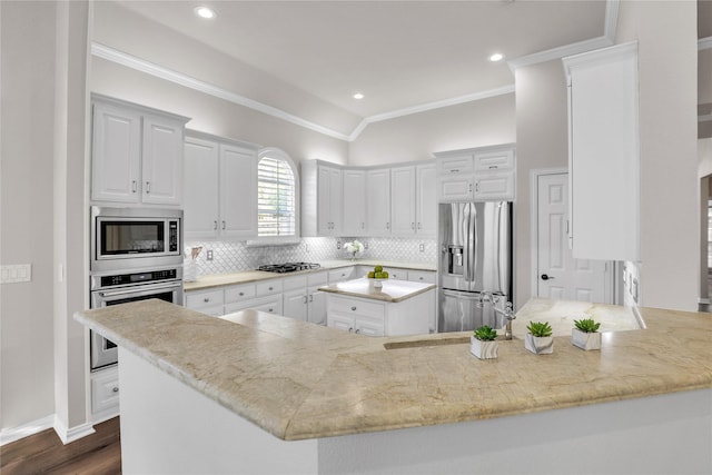 kitchen featuring crown molding, appliances with stainless steel finishes, backsplash, white cabinets, and kitchen peninsula