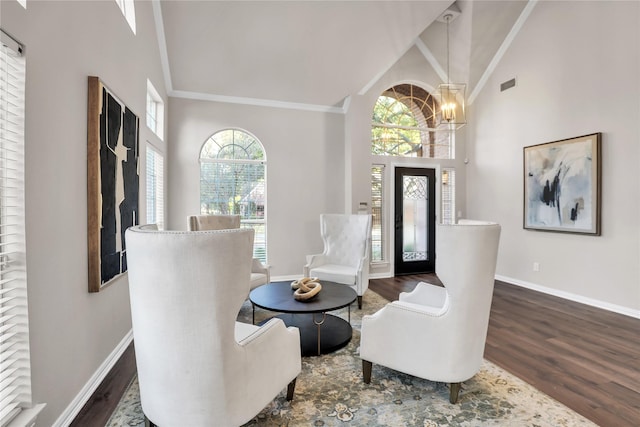 living area featuring ornamental molding, dark hardwood / wood-style flooring, a chandelier, and high vaulted ceiling