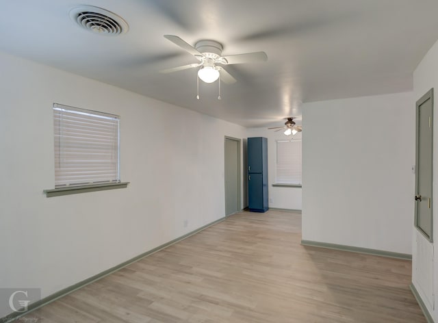 empty room featuring ceiling fan, light wood finished floors, visible vents, and baseboards