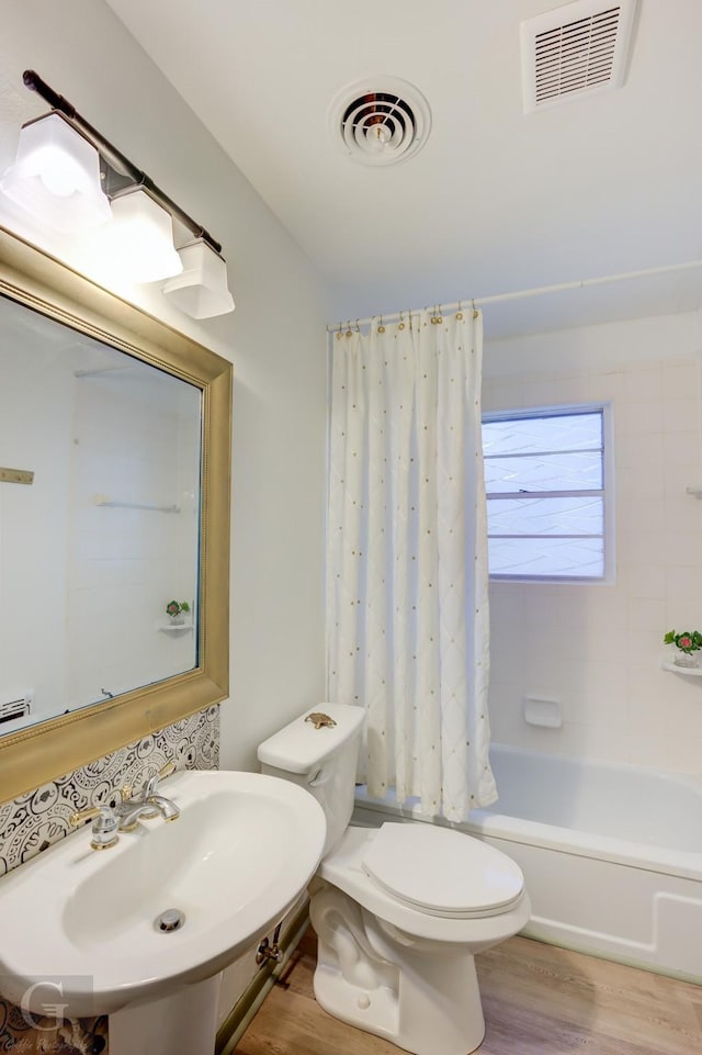 full bathroom featuring hardwood / wood-style flooring, shower / bath combo, sink, and toilet