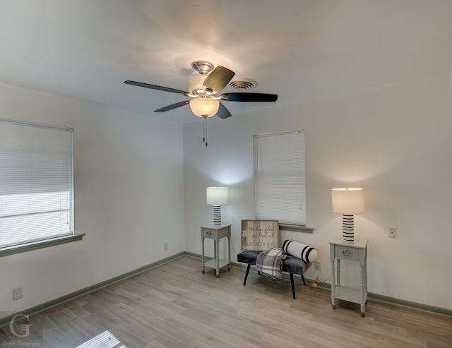 living area featuring ceiling fan, baseboards, and wood finished floors