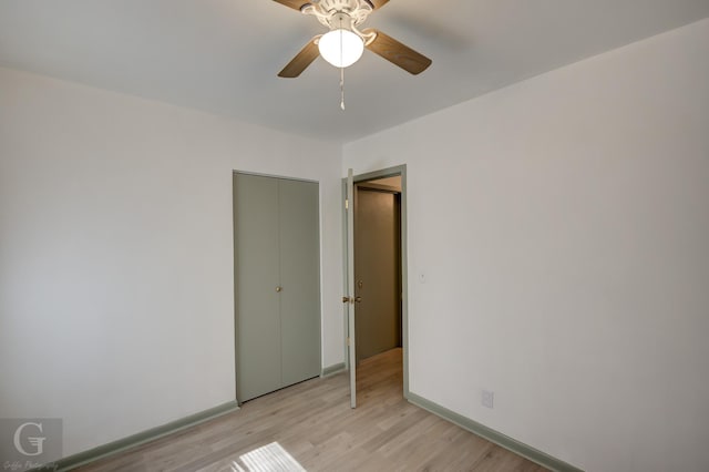 unfurnished bedroom with light wood-style floors, ceiling fan, baseboards, and a closet