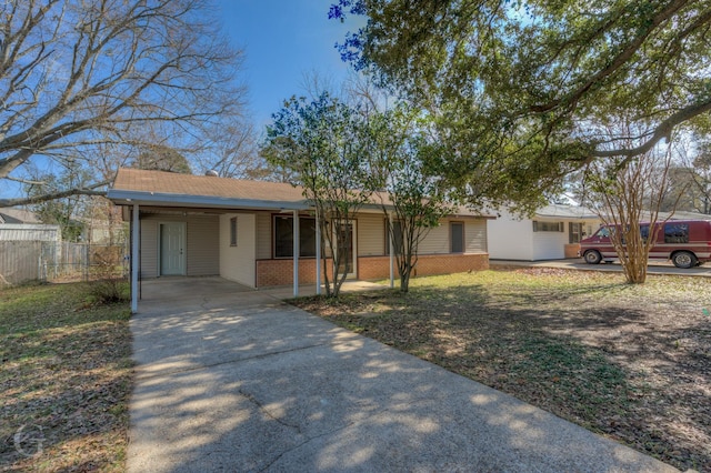 ranch-style home with a carport, fence, concrete driveway, and brick siding