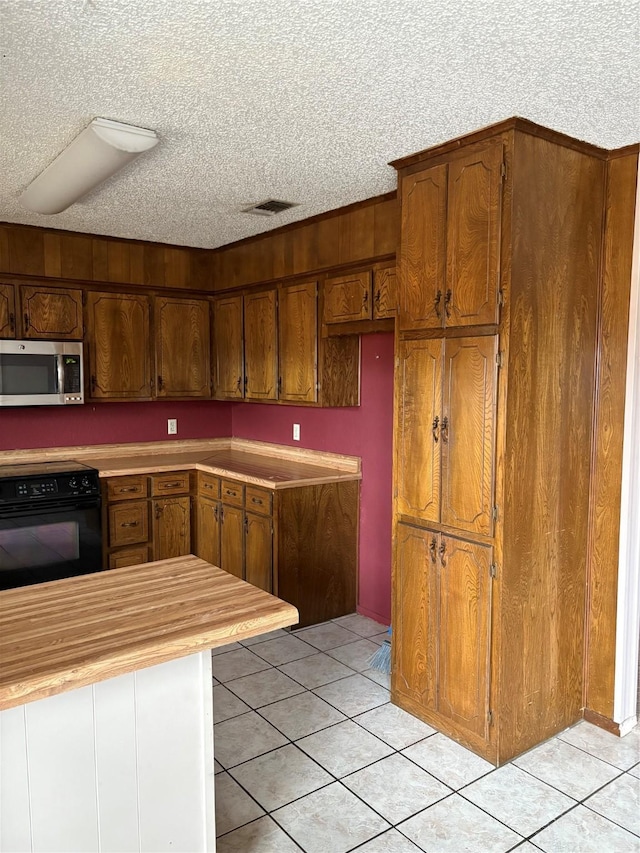 kitchen with range, a textured ceiling, and light tile patterned floors