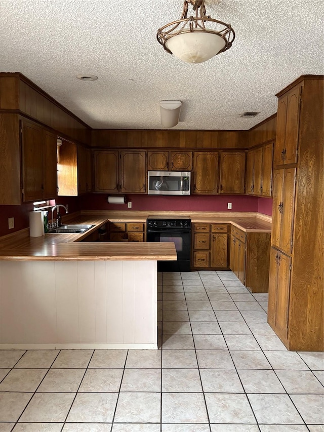 kitchen with sink, stove, light tile patterned floors, kitchen peninsula, and a textured ceiling