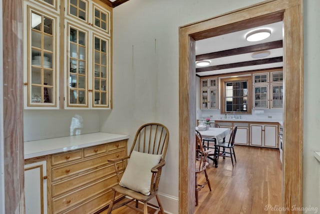 dining space featuring beam ceiling, light hardwood / wood-style floors, and sink