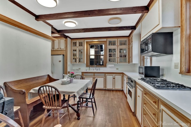 kitchen featuring stainless steel appliances, cream cabinets, sink, and light wood-type flooring