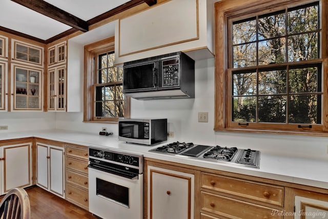 kitchen featuring stainless steel appliances, beam ceiling, light hardwood / wood-style floors, and white cabinets