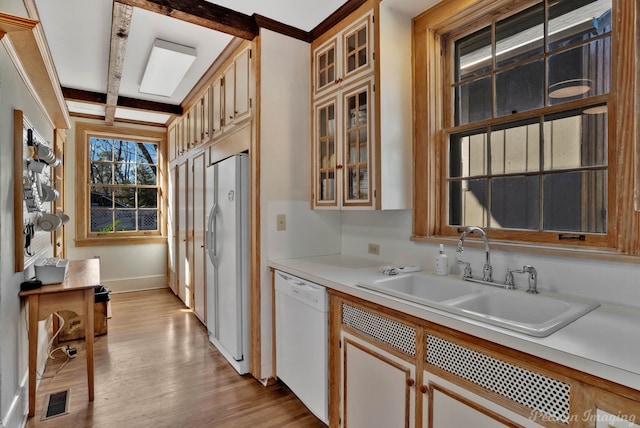 kitchen featuring beam ceiling, sink, white appliances, and light wood-type flooring