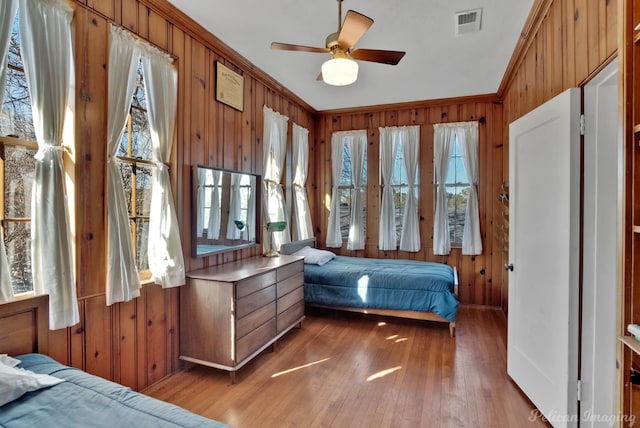 bedroom featuring multiple windows, wood-type flooring, ornamental molding, and ceiling fan