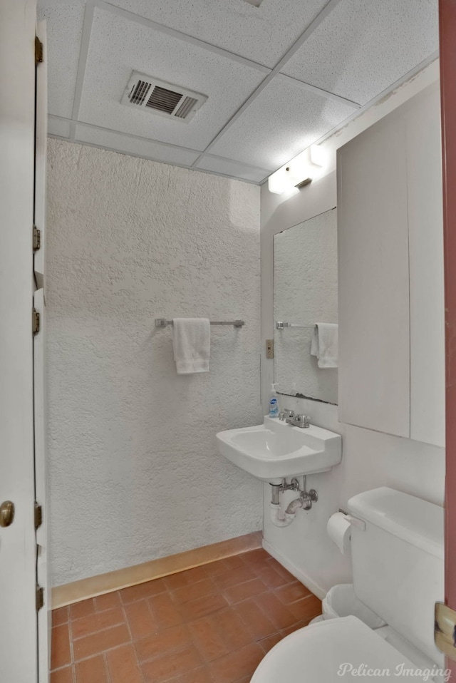 bathroom featuring a paneled ceiling, sink, and tile patterned flooring