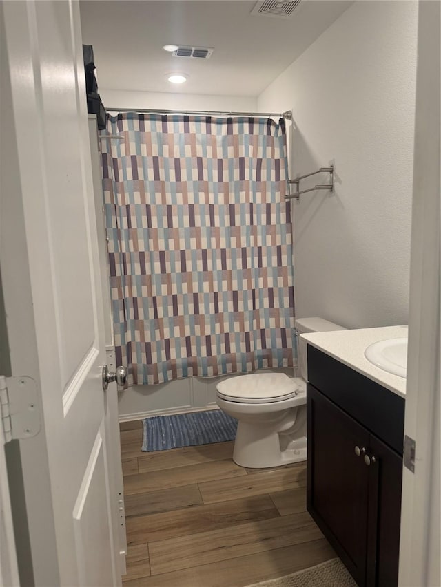 full bathroom with hardwood / wood-style flooring, vanity, toilet, and shower / tub combo