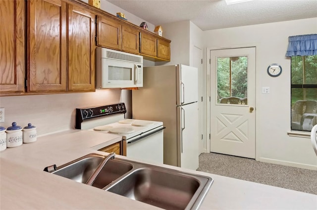 kitchen featuring white appliances, sink, and a textured ceiling