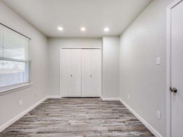 unfurnished bedroom featuring light wood-type flooring and a closet