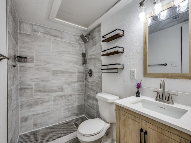 bathroom with vanity, toilet, and a tile shower