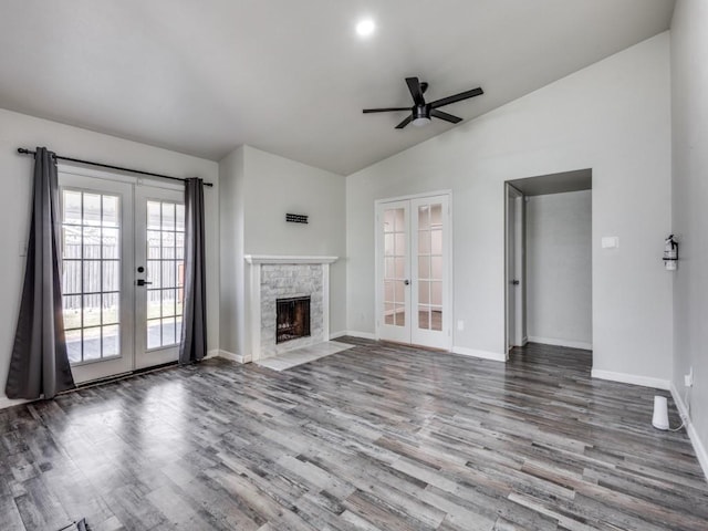 unfurnished living room with french doors, a stone fireplace, vaulted ceiling, and hardwood / wood-style floors