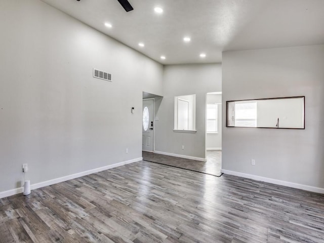 unfurnished living room with ceiling fan, hardwood / wood-style floors, and a high ceiling