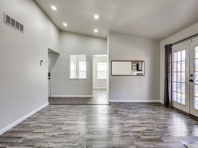 unfurnished living room featuring high vaulted ceiling, light hardwood / wood-style floors, and french doors