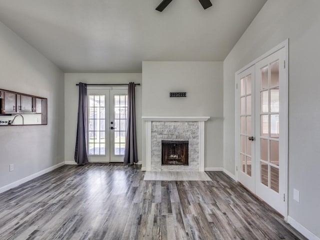 unfurnished living room with french doors, ceiling fan, a fireplace, and light hardwood / wood-style flooring